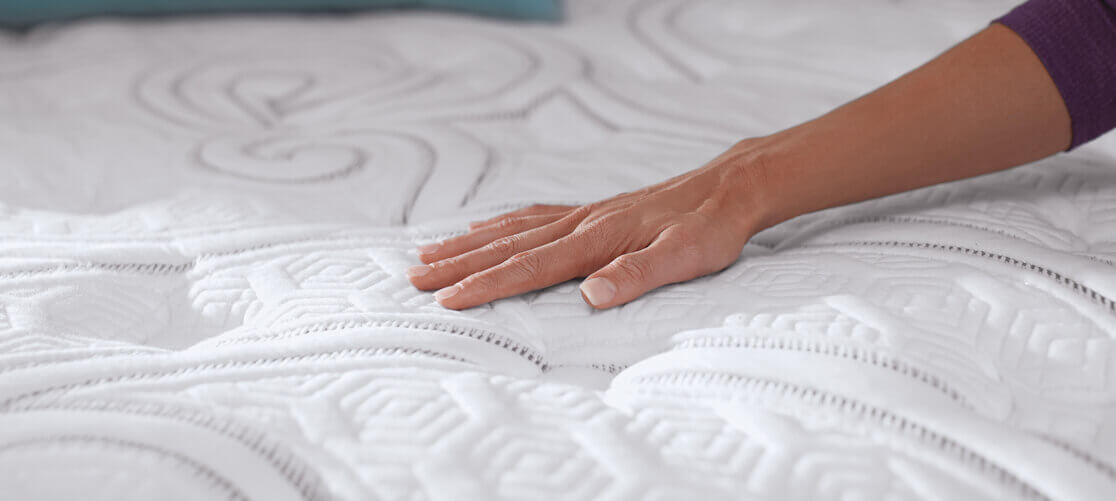 Hand touching textured white mattress surface