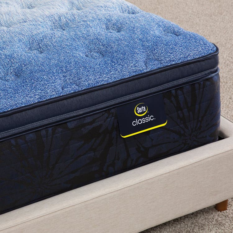 Corner of Serta classic brecon plush pillow top mattress sitting in a beige bed frame ||feel: Plush pillow top ||level: enhanced